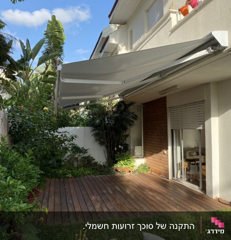 סוכך אפור פתוח מעל מרפסת עץ בגינה ירוקה